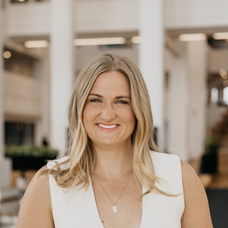Callan Faulkner, smiling headshot in a white sleeveless top, blonde hair down to her shoulders